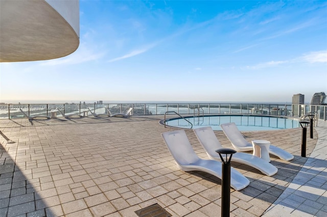 view of swimming pool featuring a patio and a water view