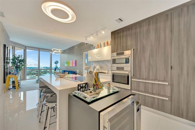 kitchen featuring light tile patterned floors, a wall of windows, a kitchen breakfast bar, a center island, and stainless steel double oven