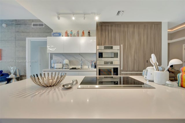 kitchen with sink, rail lighting, black electric stovetop, white cabinets, and stainless steel double oven