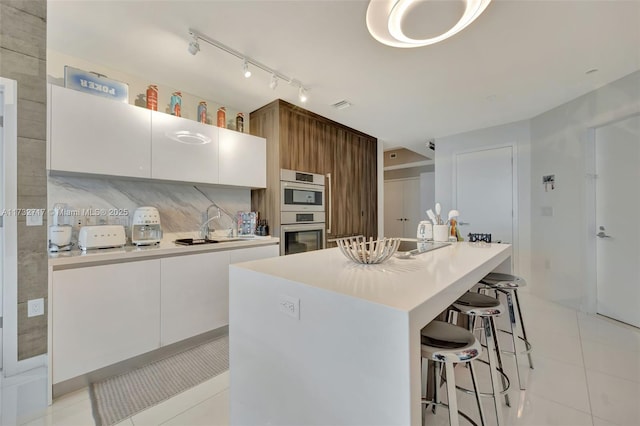 kitchen featuring white cabinetry, light tile patterned flooring, and a center island with sink