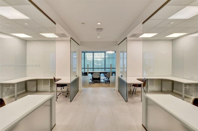 hallway featuring a drop ceiling and light tile patterned floors