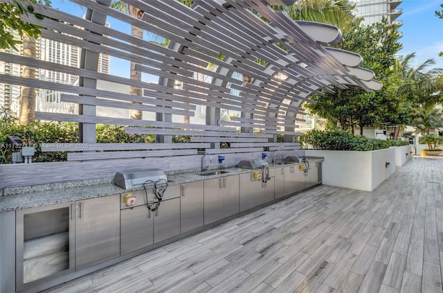 deck featuring an outdoor kitchen, a pergola, sink, and area for grilling