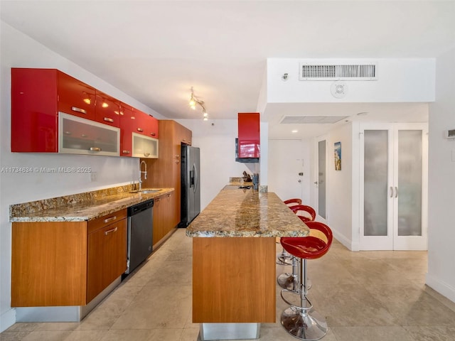 kitchen with a kitchen bar, sink, appliances with stainless steel finishes, kitchen peninsula, and light stone countertops