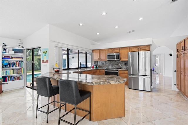 kitchen with a breakfast bar area, decorative backsplash, dark stone counters, kitchen peninsula, and stainless steel appliances