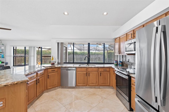 kitchen with sink, light tile patterned floors, appliances with stainless steel finishes, light stone countertops, and decorative backsplash