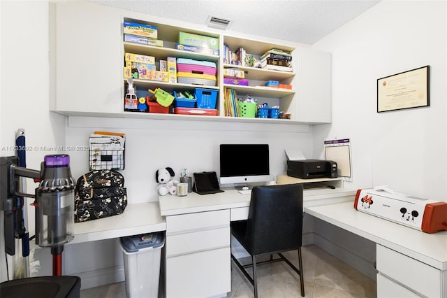 office with built in desk, a textured ceiling, and light tile patterned floors