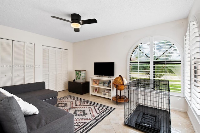 living room featuring ceiling fan, light tile patterned floors, and a textured ceiling