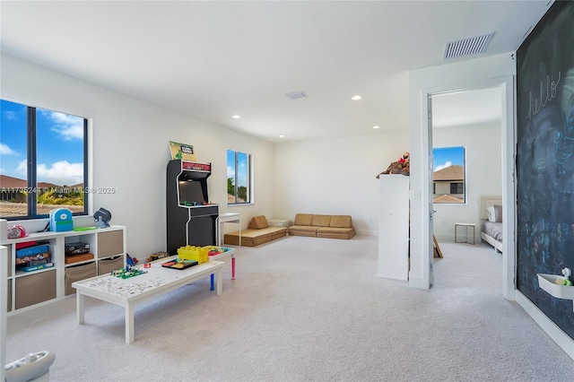 recreation room featuring light carpet and plenty of natural light