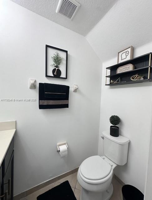 bathroom featuring vanity, vaulted ceiling, toilet, and a textured ceiling