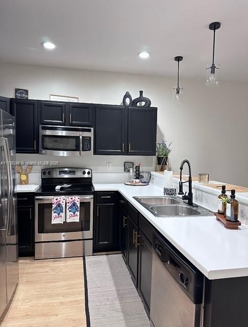 kitchen with pendant lighting, sink, light hardwood / wood-style flooring, stainless steel appliances, and kitchen peninsula