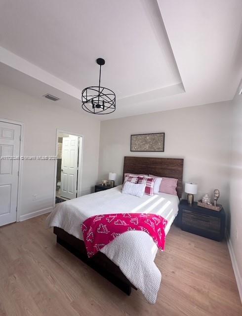 bedroom featuring light hardwood / wood-style floors and a tray ceiling