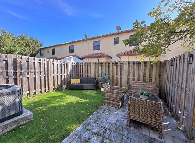 rear view of house featuring central AC unit, a lawn, outdoor lounge area, and a patio