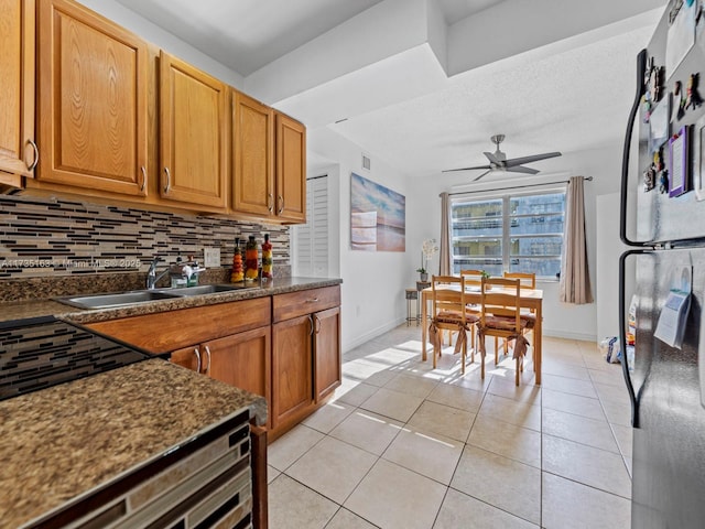 kitchen with sink, light tile patterned floors, stainless steel refrigerator, ceiling fan, and tasteful backsplash