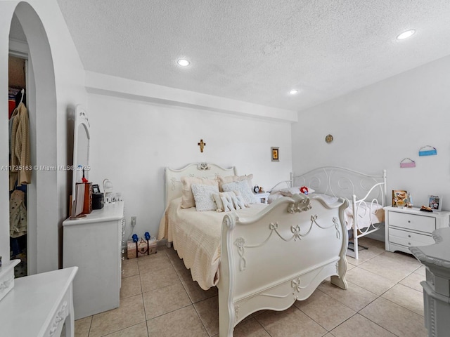 bedroom with a textured ceiling and light tile patterned floors