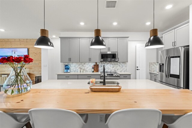 kitchen with stainless steel appliances, hanging light fixtures, sink, and gray cabinetry