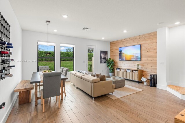 living room with wooden walls and light hardwood / wood-style flooring