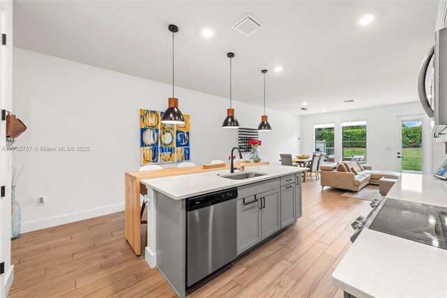 kitchen with sink, stainless steel dishwasher, gray cabinets, an island with sink, and pendant lighting