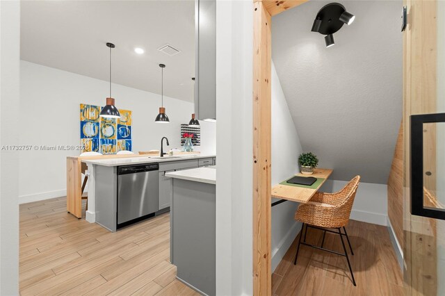 kitchen featuring a kitchen bar, decorative light fixtures, dishwasher, and light hardwood / wood-style flooring