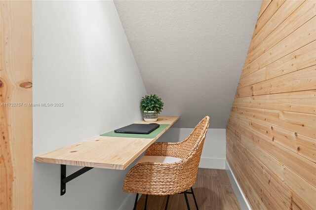 office featuring hardwood / wood-style flooring, lofted ceiling, and wood walls