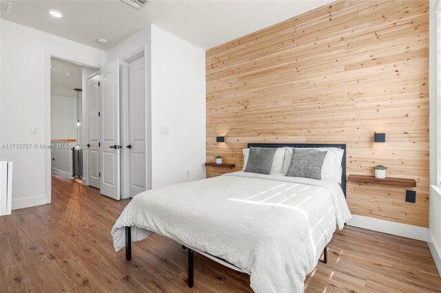 bedroom featuring light hardwood / wood-style flooring and wooden walls