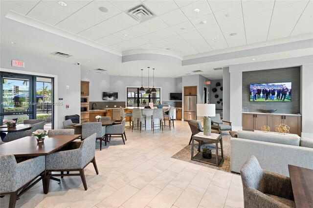 living room with a tray ceiling, sink, and light tile patterned floors