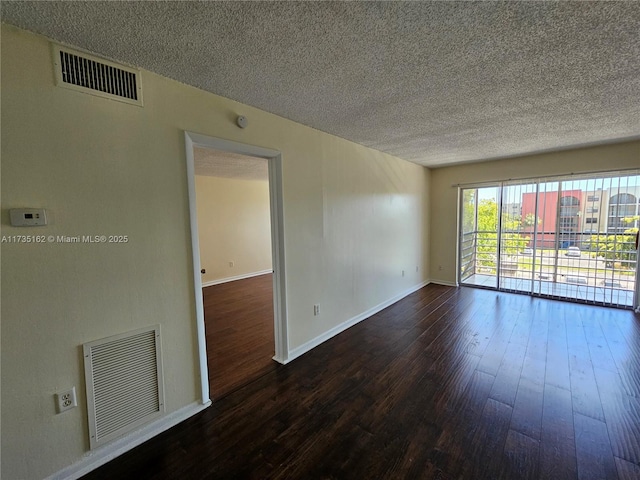 spare room featuring a textured ceiling and dark hardwood / wood-style flooring