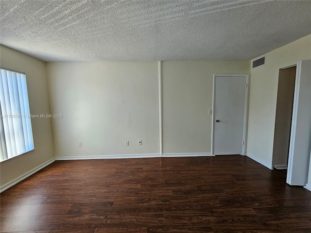 empty room with dark wood-type flooring and a textured ceiling