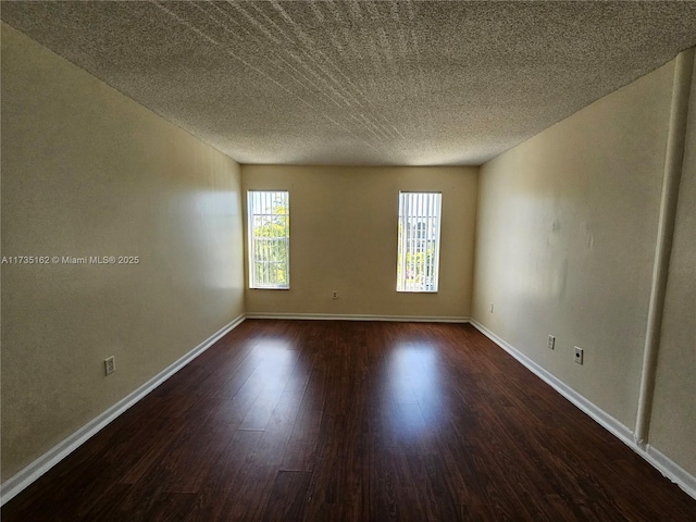 unfurnished room with dark hardwood / wood-style flooring and a textured ceiling