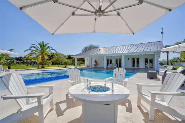 view of pool with french doors, an in ground hot tub, a patio area, and a fire pit