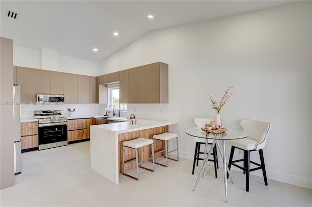 kitchen with stainless steel electric stove, a kitchen breakfast bar, sink, and kitchen peninsula