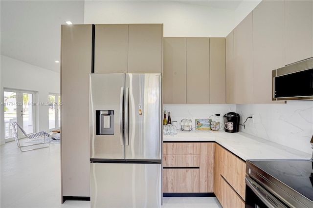 kitchen with light stone countertops, appliances with stainless steel finishes, light brown cabinets, and decorative backsplash