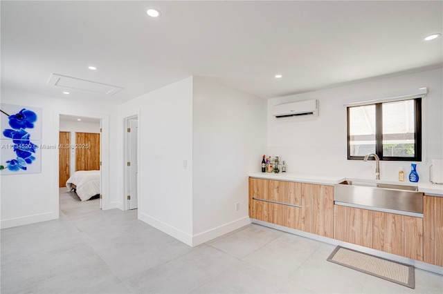 kitchen with light brown cabinetry, a wall mounted AC, and sink