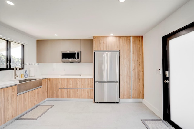 kitchen featuring appliances with stainless steel finishes, sink, light brown cabinetry, and decorative backsplash