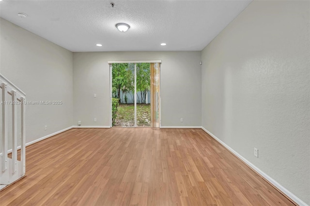 empty room with a textured ceiling and light hardwood / wood-style floors