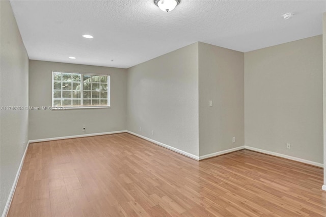 empty room with light hardwood / wood-style floors and a textured ceiling