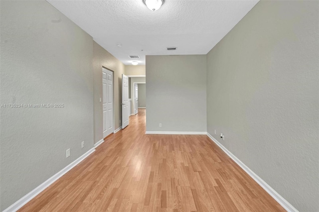 spare room featuring light hardwood / wood-style floors and a textured ceiling