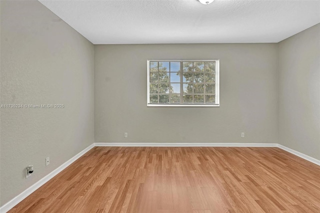 spare room featuring a textured ceiling and light wood-type flooring