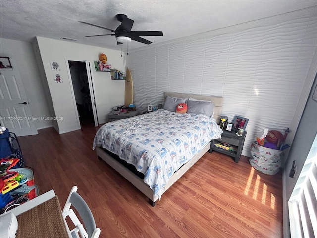 bedroom featuring ceiling fan, hardwood / wood-style floors, and a textured ceiling