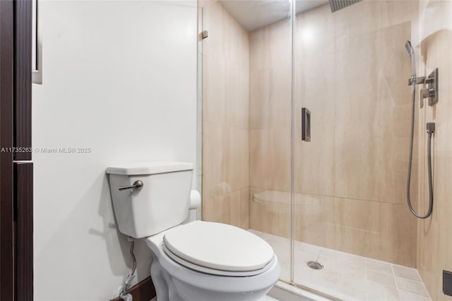 bathroom featuring a shower with door and toilet