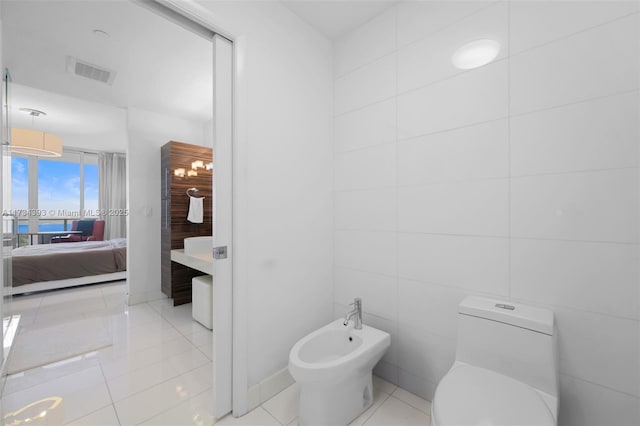 bathroom with tile patterned flooring, a bidet, tile walls, and toilet