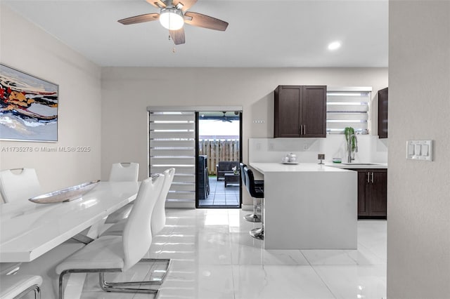 kitchen with ceiling fan, dark brown cabinets, and a kitchen bar