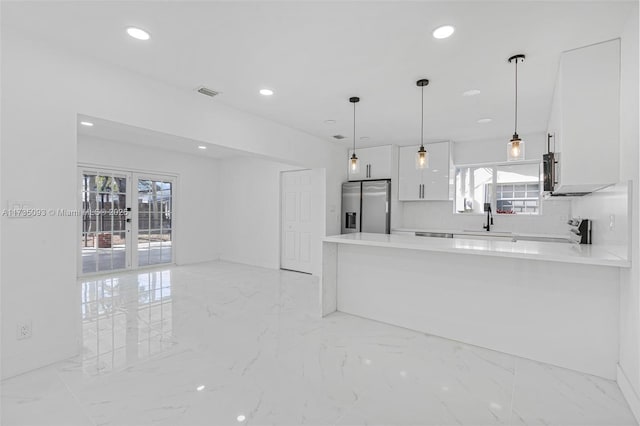 kitchen featuring sink, white cabinets, stainless steel fridge, hanging light fixtures, and kitchen peninsula