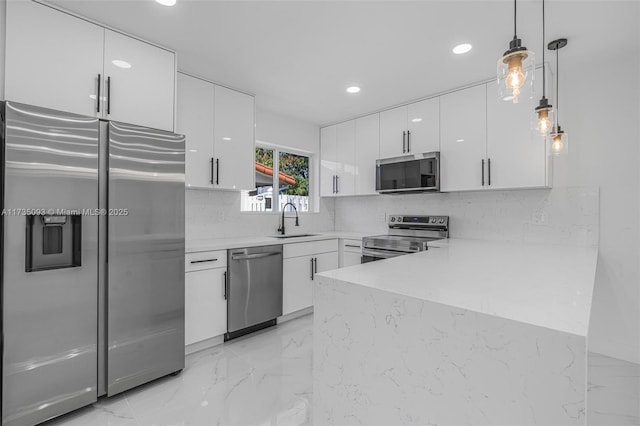 kitchen featuring sink, stainless steel appliances, hanging light fixtures, and white cabinets