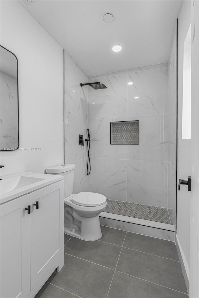 bathroom featuring vanity, toilet, and a tile shower