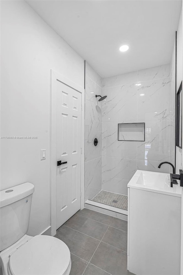 bathroom with vanity, tile patterned floors, toilet, and a tile shower