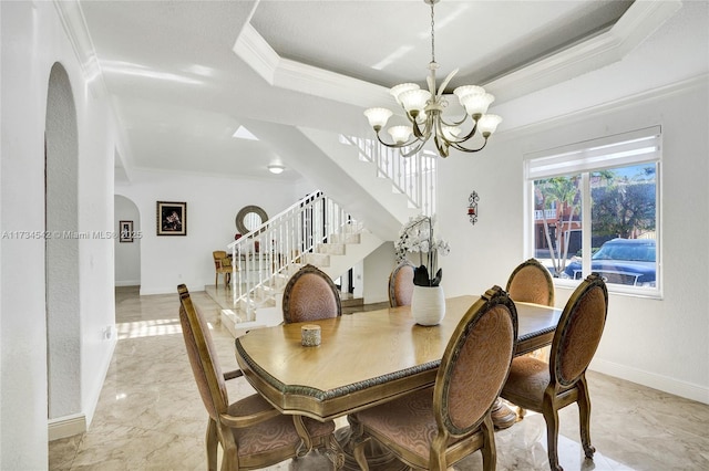 dining area featuring a raised ceiling, ornamental molding, and a chandelier