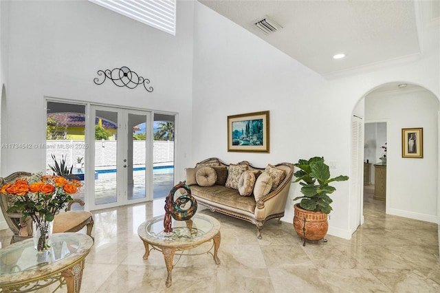 living room featuring french doors, a towering ceiling, and crown molding