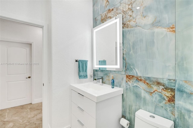 bathroom with decorative backsplash, vanity, toilet, and tile walls