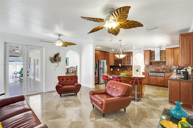 living room with french doors, ceiling fan, and a textured ceiling