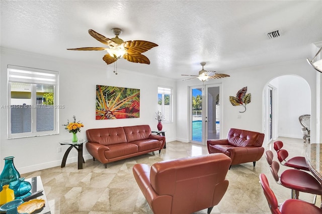 living room with crown molding, ceiling fan, and a textured ceiling